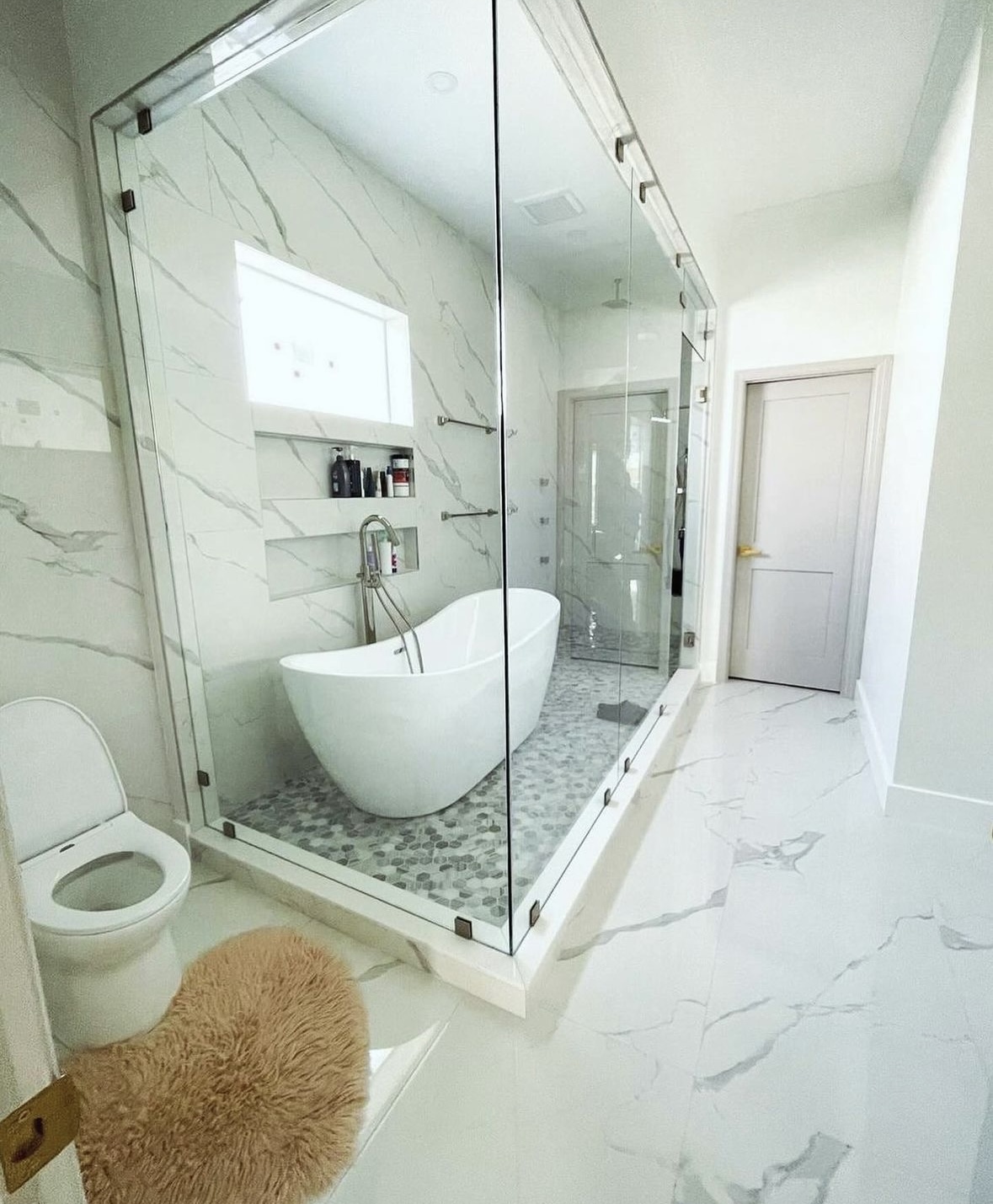 Walk-in glass shower with marble tile